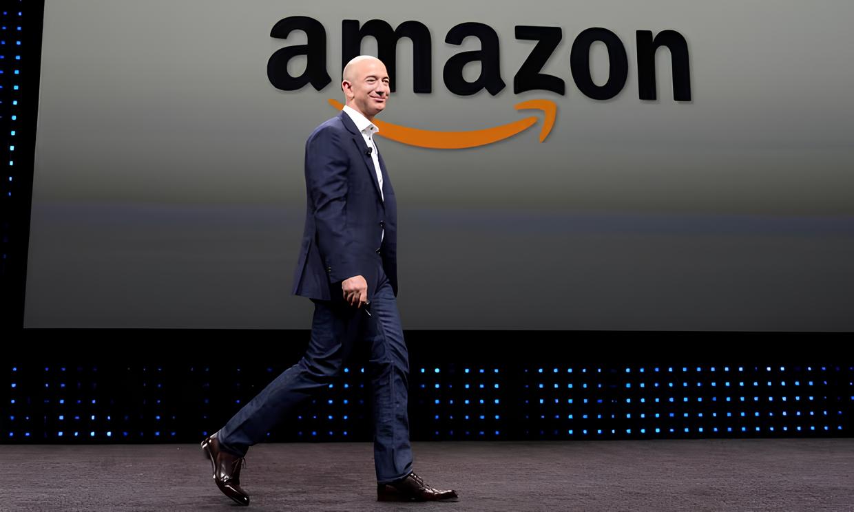 Jeff Bezos berdiri di depan logo Amazon, e-commerce raksasa Amerika Serikat.