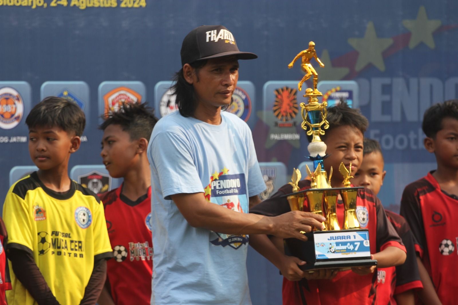 Ketua Panpel Pendowo Cup U-10 2024 Sutriyono (kiri) menyerahkan trofi juara kepada kapten Muda Ceria Jember