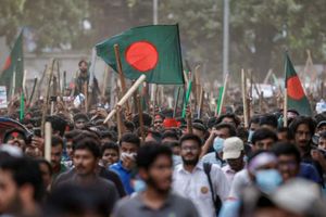 Para pengunjuk rasa merayakan di samping potret Perdana Menteri Sheikh Hasina yang dirusak setelah berita pengunduran dirinya, di Dhaka, Bangladesh.