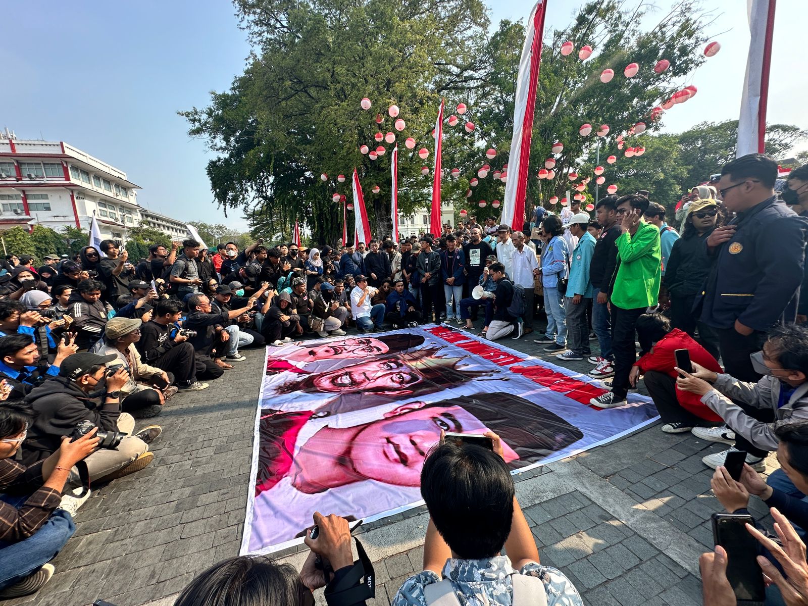 Demonstran membentangkan banner besar yang isinya menyindir dinasti Jokowi dalam aksi di Balai Kota Solo, Kamis, 22 Agustus 2024. (Kredit AJI)