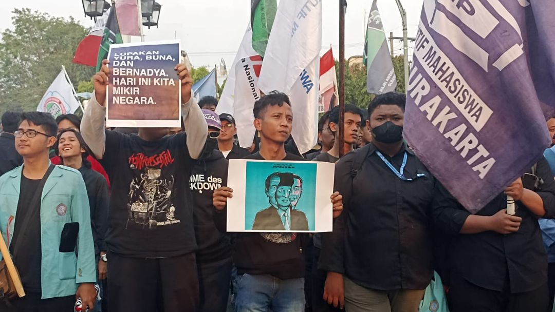 Demonstran membawa poster yang isinya menyindir pemerintahan Joko Widodo dalam aksi di Balai Kota Solo,  Kamis, 22 Agustus 2024. (Chrisna Chanis Cara/TrenAsia)