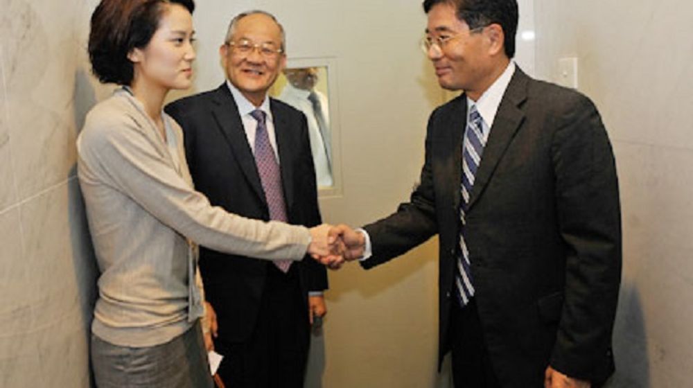 Elaine Low, berjabat tangan dengan Duta Besar Jepang untuk Singapura Yoichi Suzuki setelah menyerahkan cek untuk digunakan bagi korban gempa, sementara ayah Elaine, Datuk Low, mengamati.