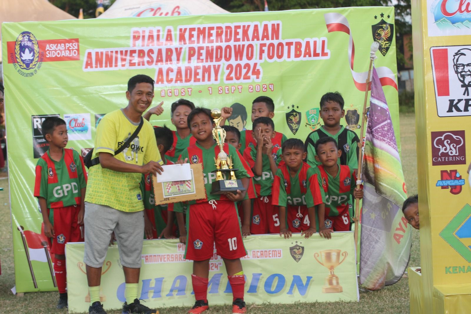 Ketua Panpel Anniversary Pendowo Football Academy Tatang menyerahkan trofi juara kepada kapten GPD Jedi Ramadhan