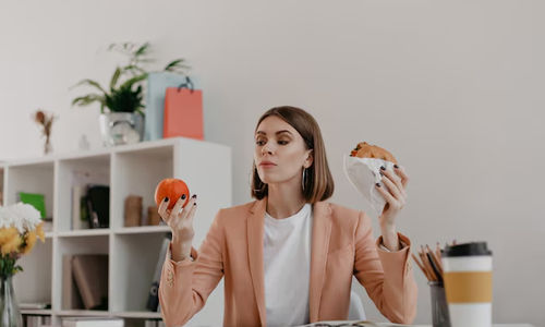 Ilustrasi wanita sedang makan camilan di meja kerja kantor.