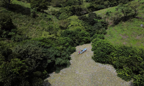 Warga berjalan di antara sampah saat bekerja dalam program yang didanai pemerintah Salvador untuk membersihkan waduk El Cerron Grande di Potonico, El Salvador, 14 September 2022.