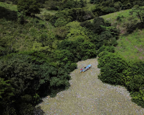 Warga berjalan di antara sampah saat bekerja dalam program yang didanai pemerintah Salvador untuk membersihkan waduk El Cerron Grande di Potonico, El Salvador, 14 September 2022.