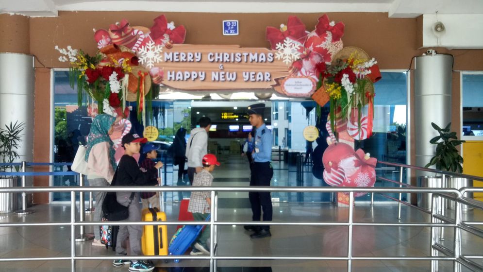 Petugas menyambut calon penumpang di pintu keberangkatan Bandara SMB II Palembang, Selasa (24/12/2024).