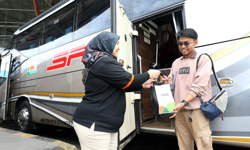 Wakil Direktur Perusahaan Otobus Siliwangi Antar Nusa (PO. SAN) Kurnia Lesari Adnan membagikan bingkisan berupa snack dan kalender kepada para penumpang bus PO.SAN di Terminal Terpadu Pulo Gebang , Jakarta Timur, Selasa 31 Desember 2024. Foto : Panji Asmoro/TrenAsia