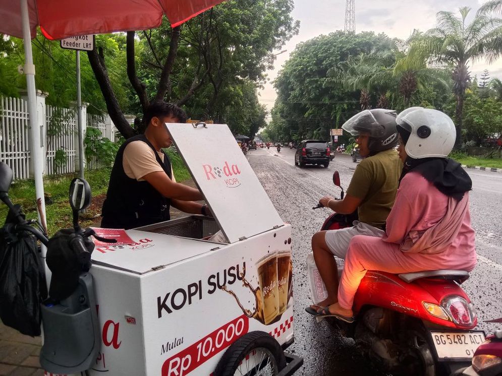 Seorang  penjual kopi keliling melayani pembeli  di kawasan Jalan POM X,  Kota Palembang, Sabtu sore (4/ 1 / 2025). 