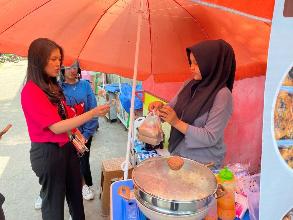 Penjual dimsum memberikan pesanan yang menggunakan plastik kepada pembeli, Palembang, Rabu (08/01/25).