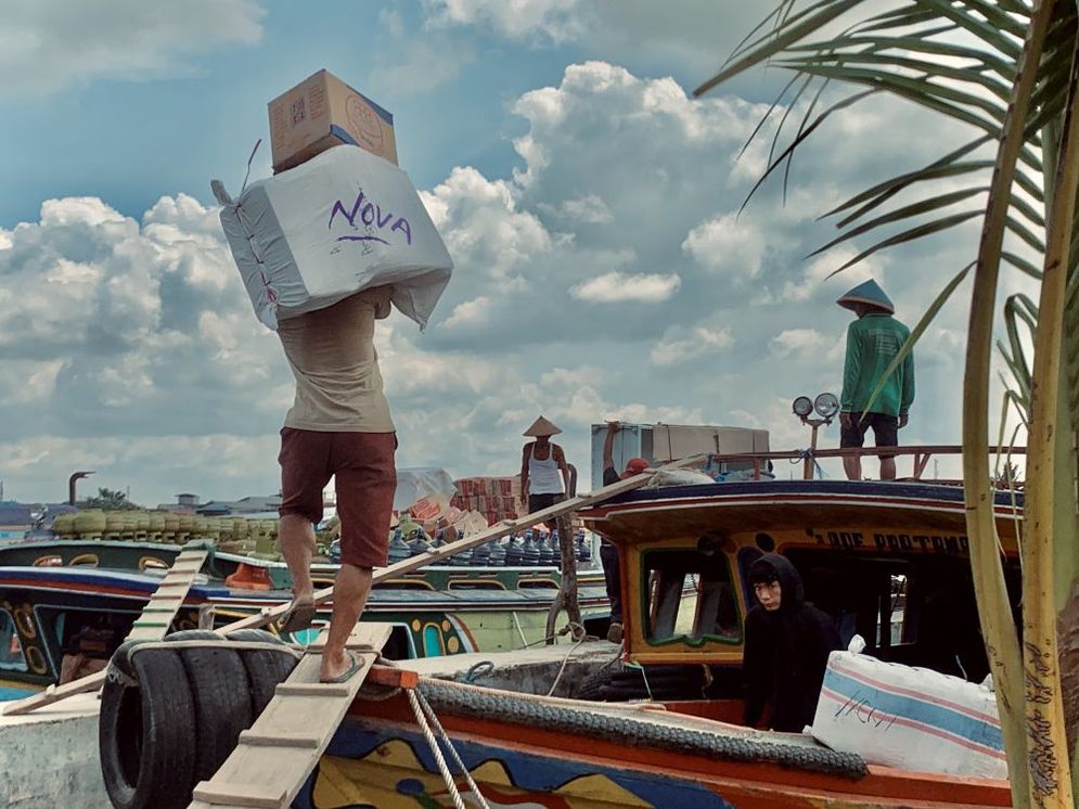 Seorang buruh angkut tengah memikul bahan makanan menuju kapal di tepian Sungai Musi, pengangkutan bahan pokok ini akan di bawa untuk didistribusikan ke  wilayah perairan Banyuasin, Rabu (8/1/2025))