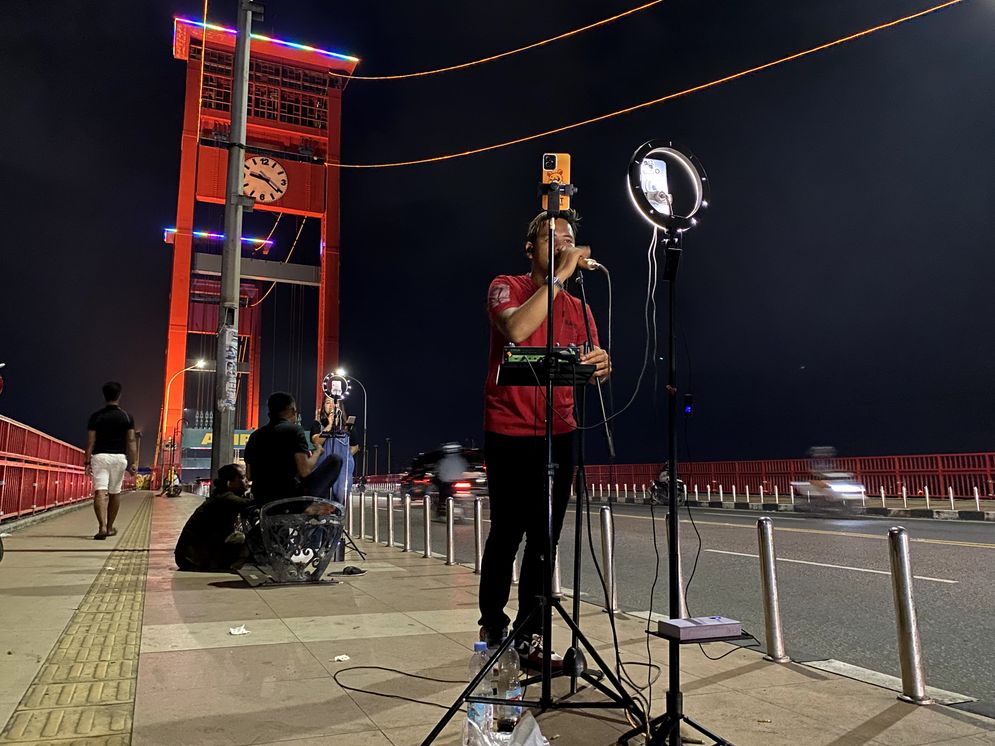 Salah seorang penyanyi live streaming Tiktok sedang beraktivitas di Jembatan Ampera, Selasa malam (14/1/2025)