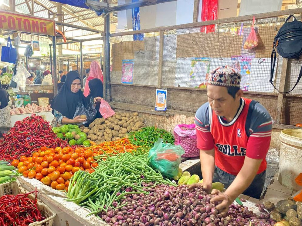 Deri seorang pedagang sayur yang sedang sibuk merapikan bawang jualannya, Palembang, Minggu (02/02/25).