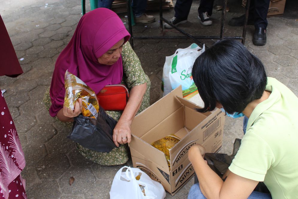 Dua orang warga tampak menyusun barang-barang yang dibeli di pasar murah yang diselenggarakan di halaman kanto Camat Sako, Senin (10/3/2025)