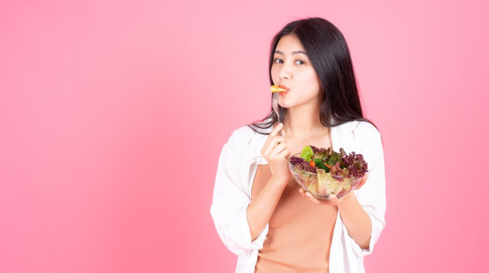 Ilustrasi wanita sedang makan salad.