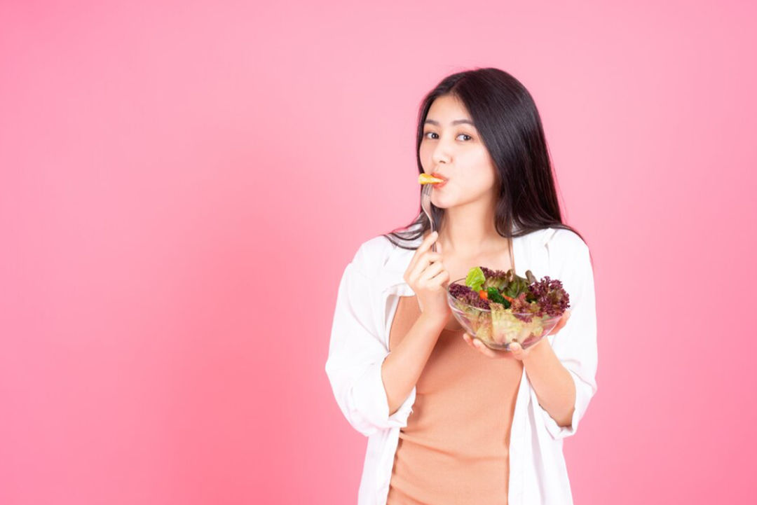 Ilustrasi wanita sedang makan salad.