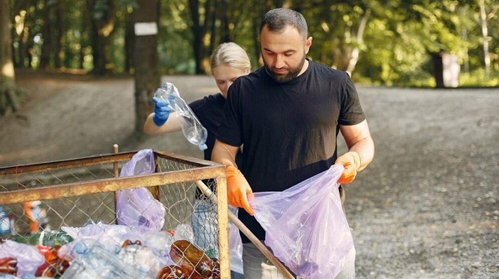 Seorang laki-laki dan perempuan sedang memilah sampah.