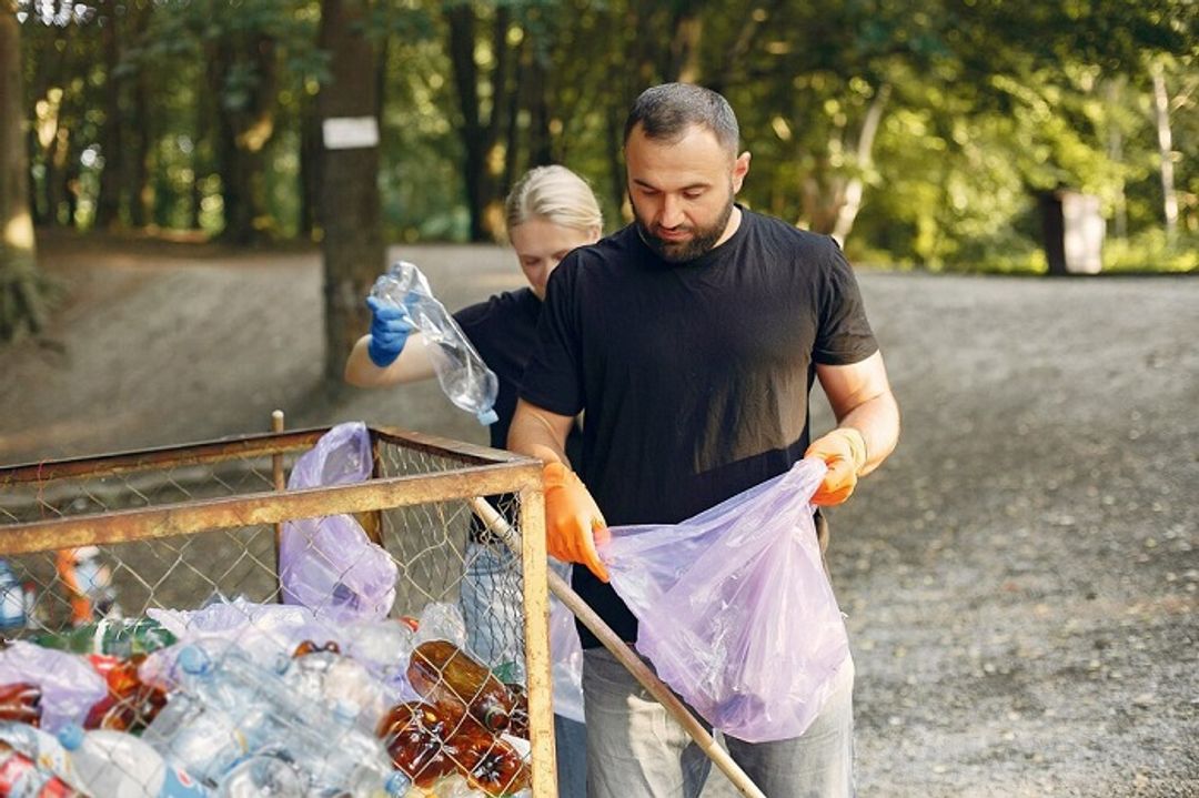 Seorang laki-laki dan perempuan sedang memilah sampah.