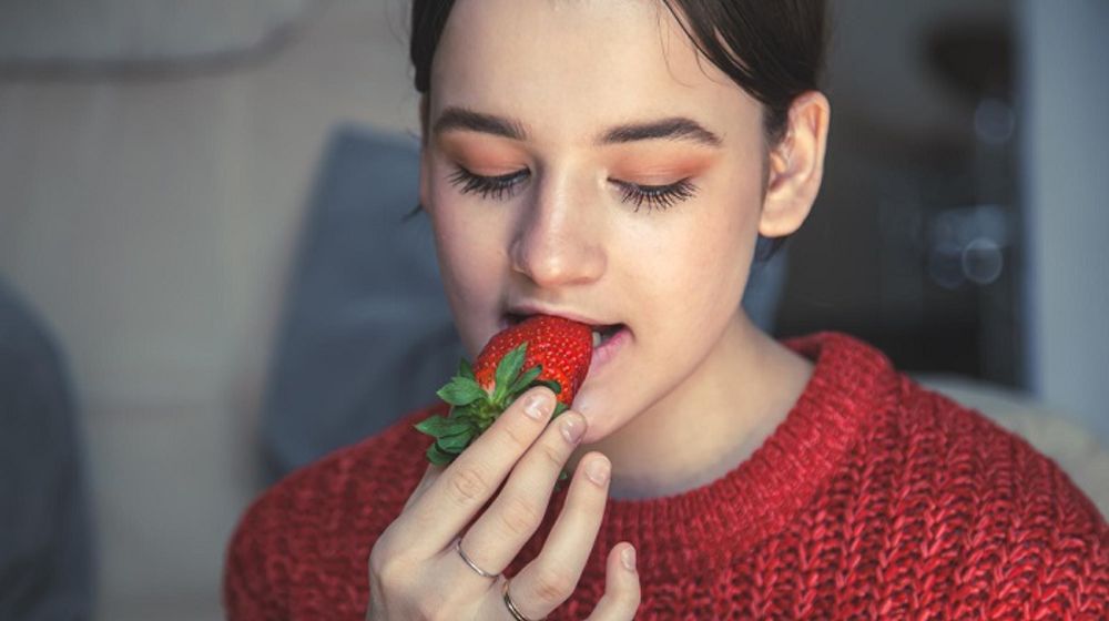 Ilustrasi wanita mengkonsumsi buah stroberi.