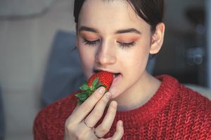 Ilustrasi wanita mengkonsumsi buah stroberi.
