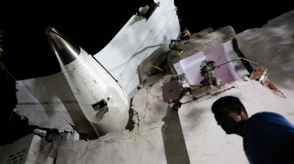 Seorang berjalan melewati puing-puing di lokasi jatuhnya pesawat setelah sebuah pesawat Air India yang hendak menuju Bandara Gatwick di London mengalami kecelakaan saat lepas landas dari bandara di Ahmedabad, India, pada 12 Juni 2025.