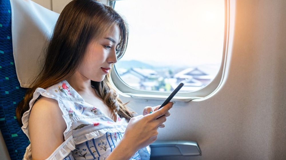 Ilustrasi wanita sedang memainkan ponsel di dalam pesawat.