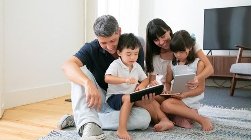 happy-parents-cute-kids-using-mobile-devices-floor-living-room_74855-8108.jpg