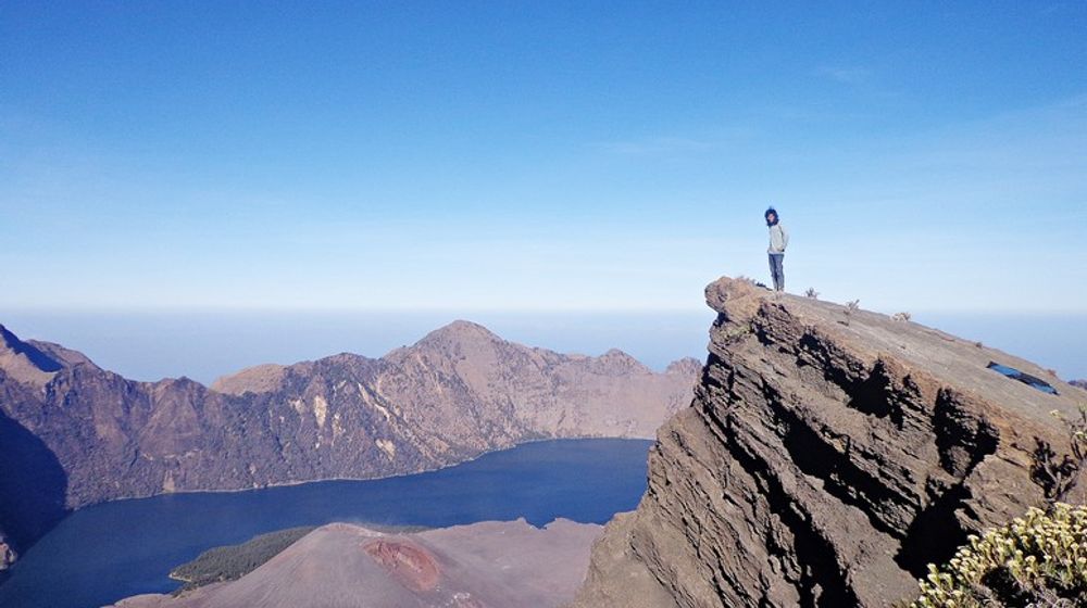 Seseorang berpose di puncak Gunung Rinjani.