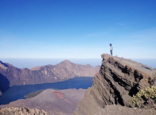 Seseorang berpose di puncak Gunung Rinjani.