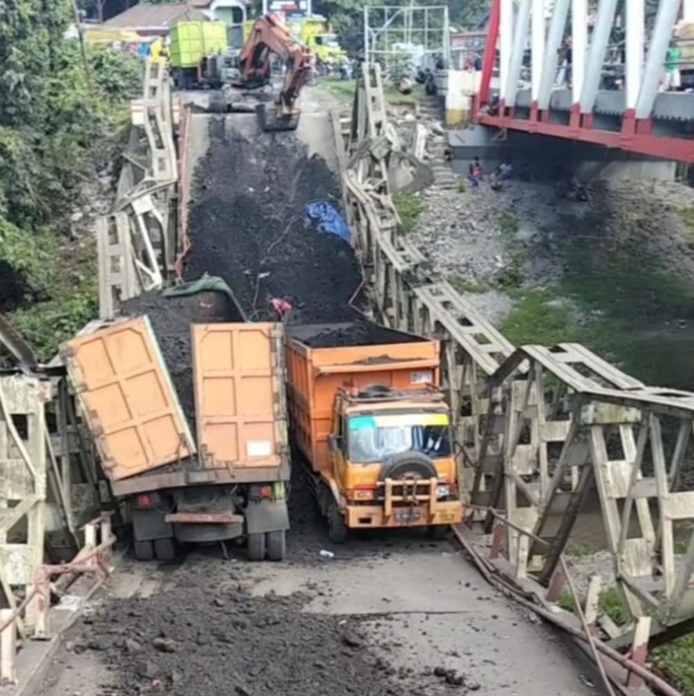 Alat berat berupaya menarik truk batu bara yang  terjebak