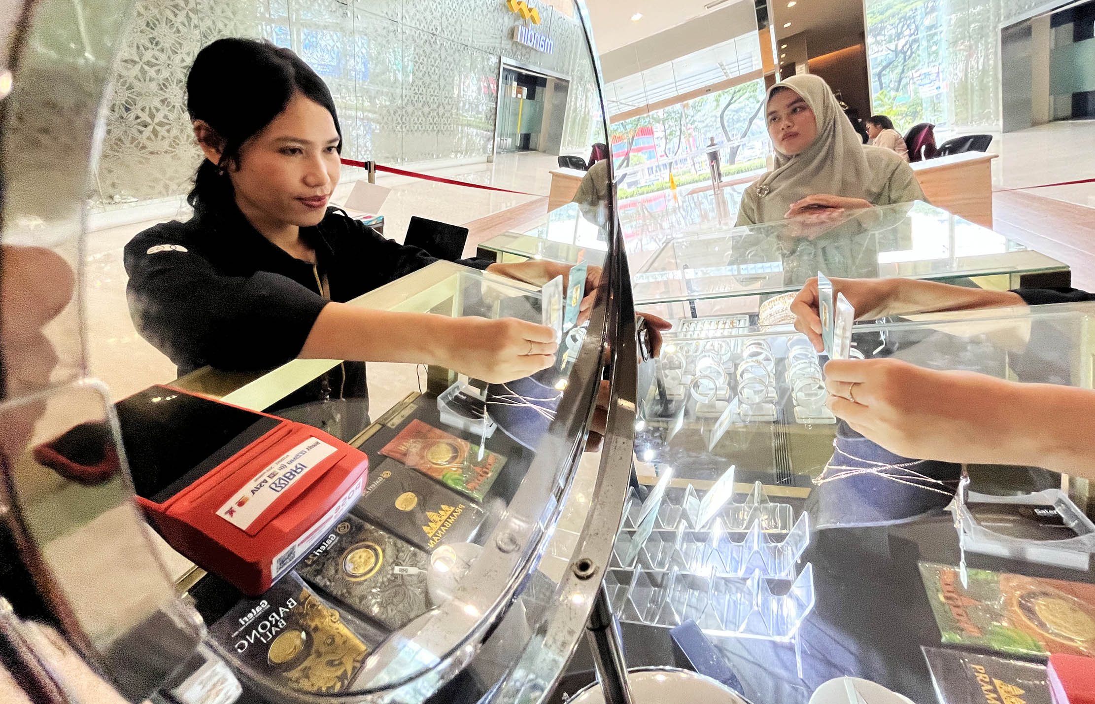 Nampak karyawan menunjukkan logam mulia di sebuah gerai emas di kawasan BSD Tangerang. Foto : Panji Asmoro/TrenAsia