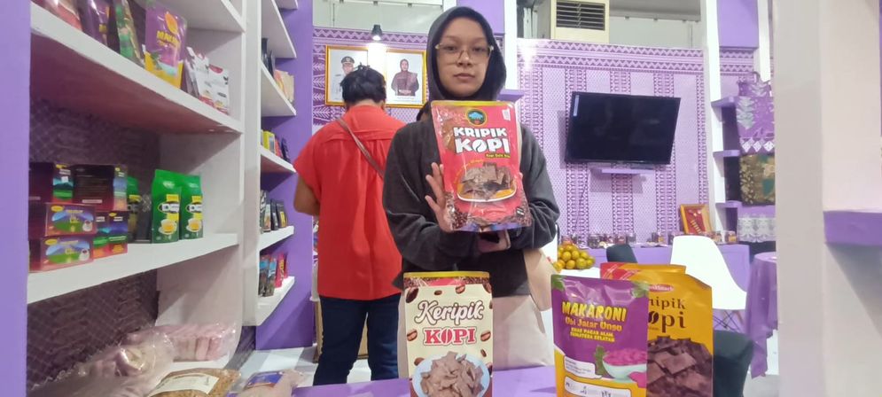 Seorang pengunjung Sirijaya Expo 2025, menunjukan  keripik kopi yang ditawarkan stan Pemkot Pagar Alam