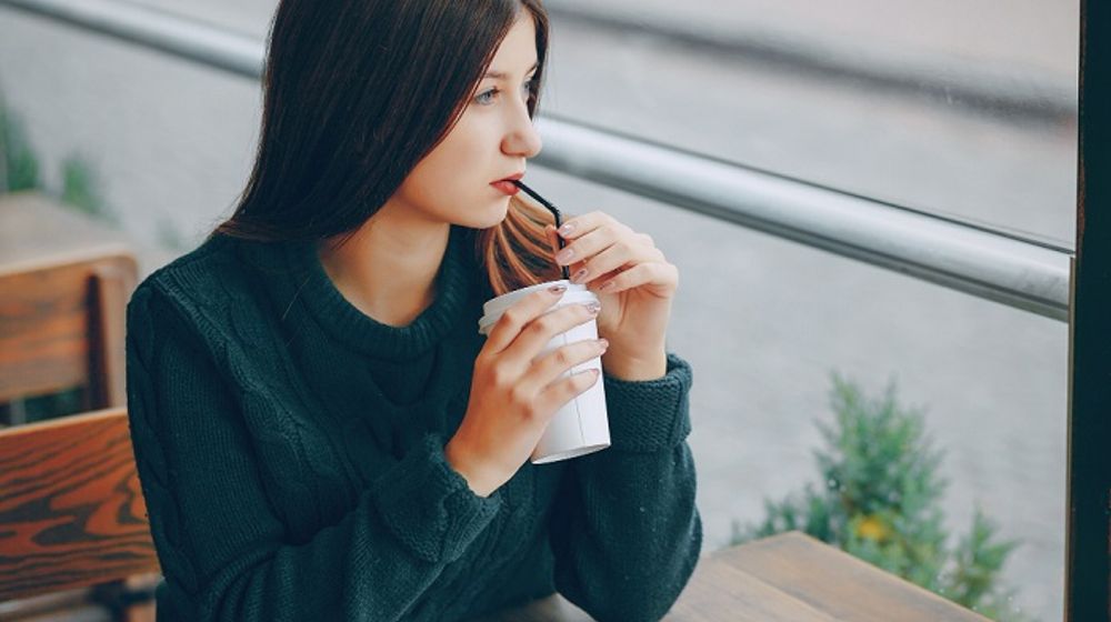 Ilustrasi wanita sedang minum kopi di luar.