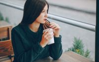 Ilustrasi wanita sedang minum kopi di luar.