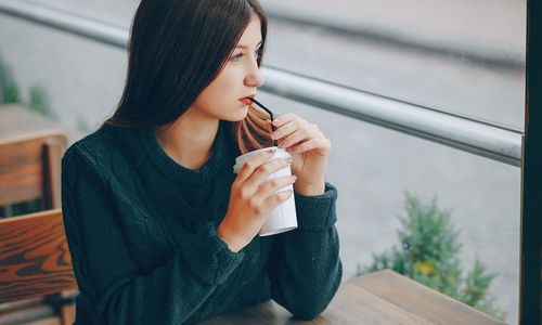 Ilustrasi wanita sedang minum kopi di luar.