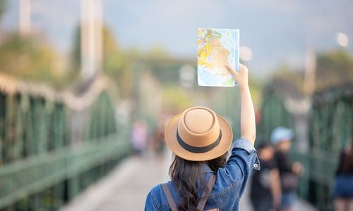 Ilustrasi seorang wisatawan membawa travel map.