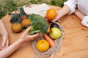 Ilustrasi wanita sedang membawa sayur dan buah, makan sehat berkelanjutan.