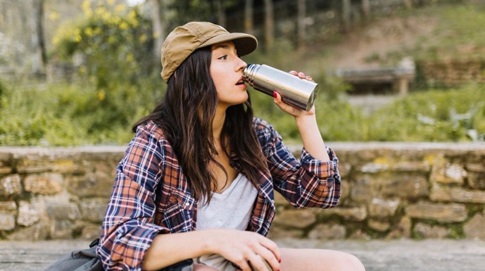 Wanita menggunakan botol minum sendiri guna mengurangi sampah plastik.