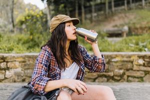 Wanita menggunakan botol minum sendiri guna mengurangi sampah plastik.