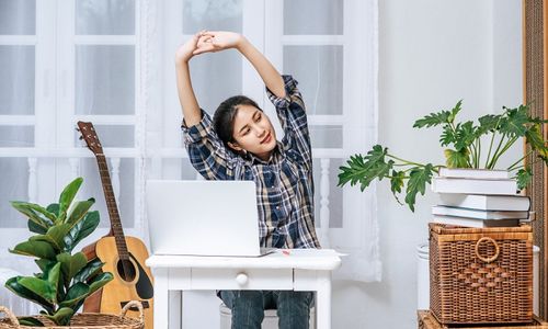 Ilustrasi orang menjalankan gaya hidup minimalis, sedang meregangkan lengan saat bekerja.
