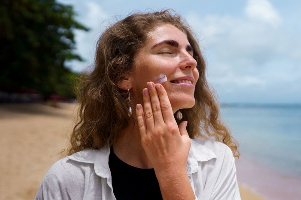 Ilustrasi wanita menggunakan sunscreen.