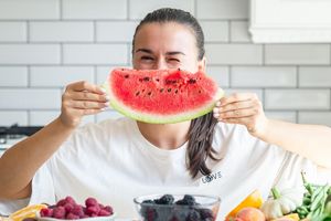 Wanita makan semangka di cuaca panas.