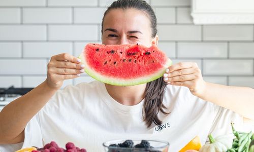 Wanita makan semangka di cuaca panas.