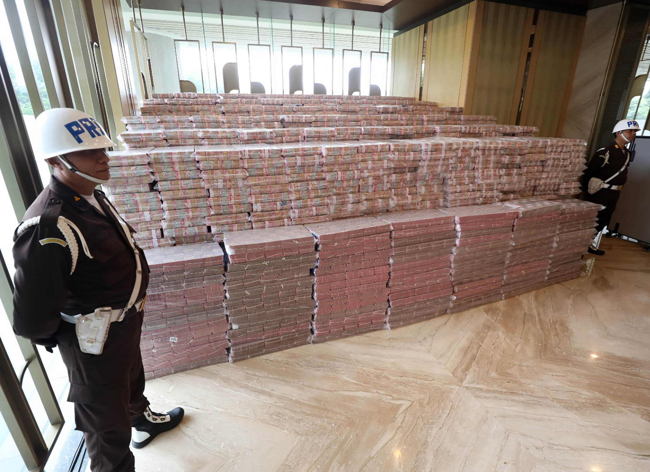 Petugas berjaga di dekat uang tunai saat penyerahan uang pengganti kerugian negara senilai Rp13,2 triliun hasil korupsi minyak kelapa sawit (CPO) di Kejaksaan Agung. Foto : Panji Asmoro/TrenAsia