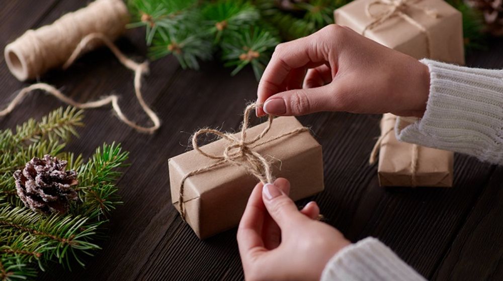 Ilustrasi seseorang sedang membuat kado natal ramah lingkungan.