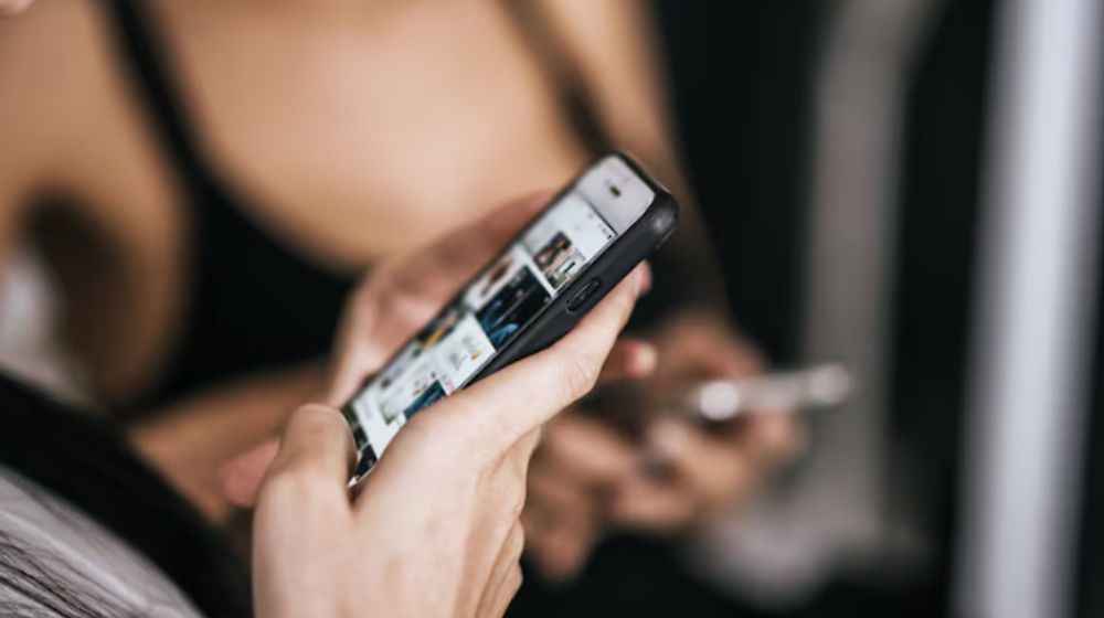 Ilustrasi seseorang menggenggam ponsel terlalu lama.