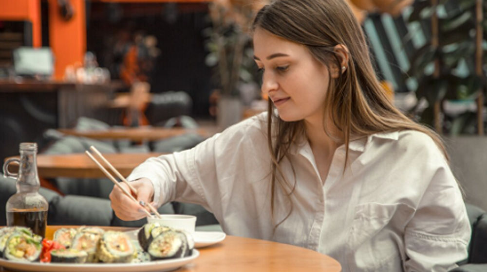 Wanita sedang menikmati sushi di tempat.