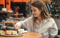 Wanita sedang menikmati sushi di tempat.