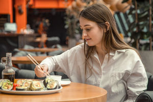 Wanita sedang menikmati sushi di tempat.