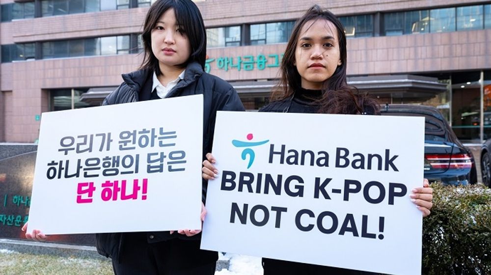 Lee Da-yeon dan Nurul Sarifah memegang papan bertuliskan tuntutan agar Hana Bank menghentikan pendanaan proyek nikel.